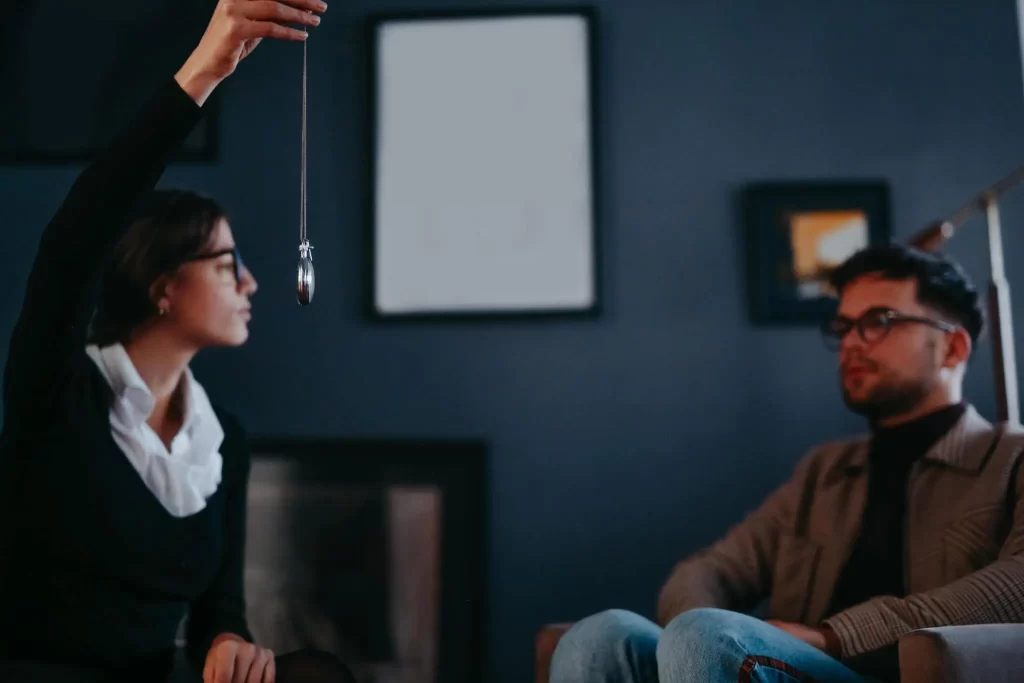 A therapist performing hypnotherapy with a male client in an office.