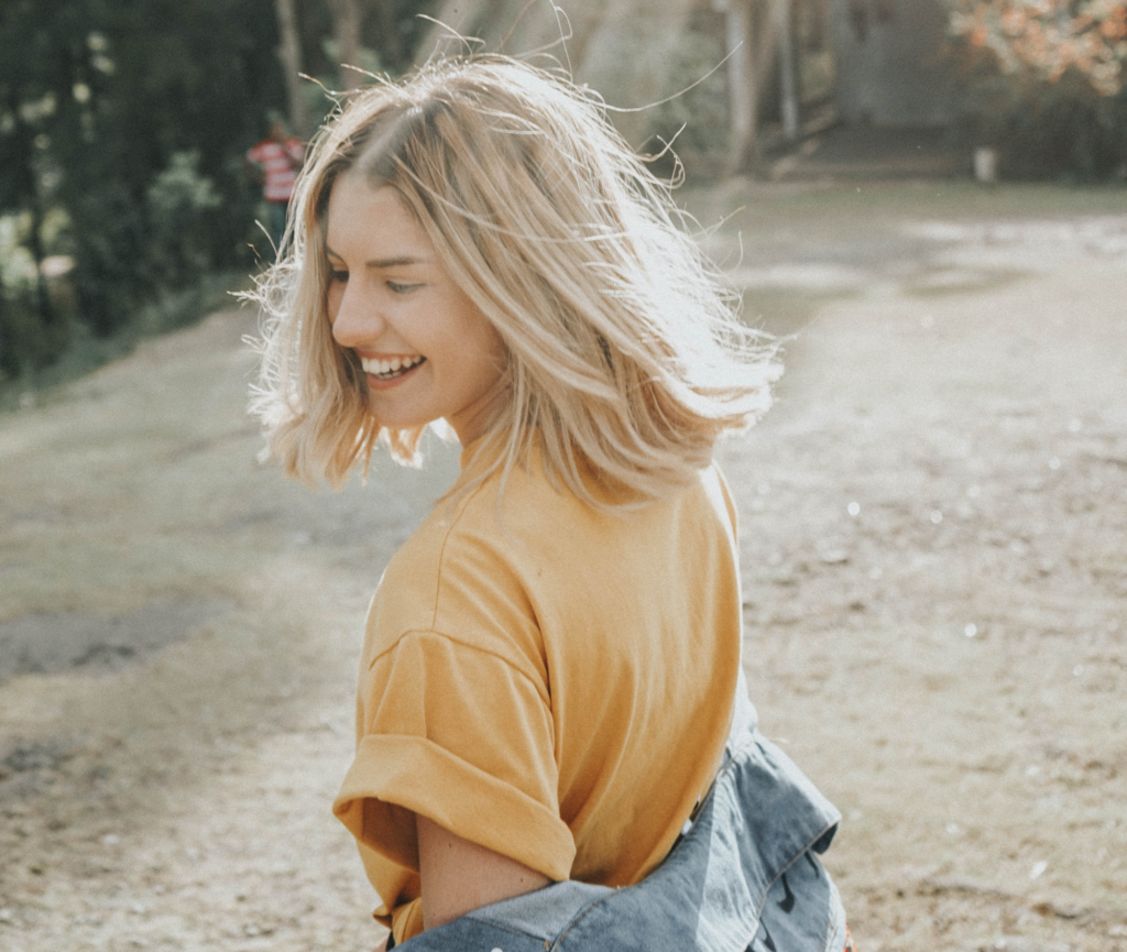 Smiling young woman outdoors, looking back over her shoulder.